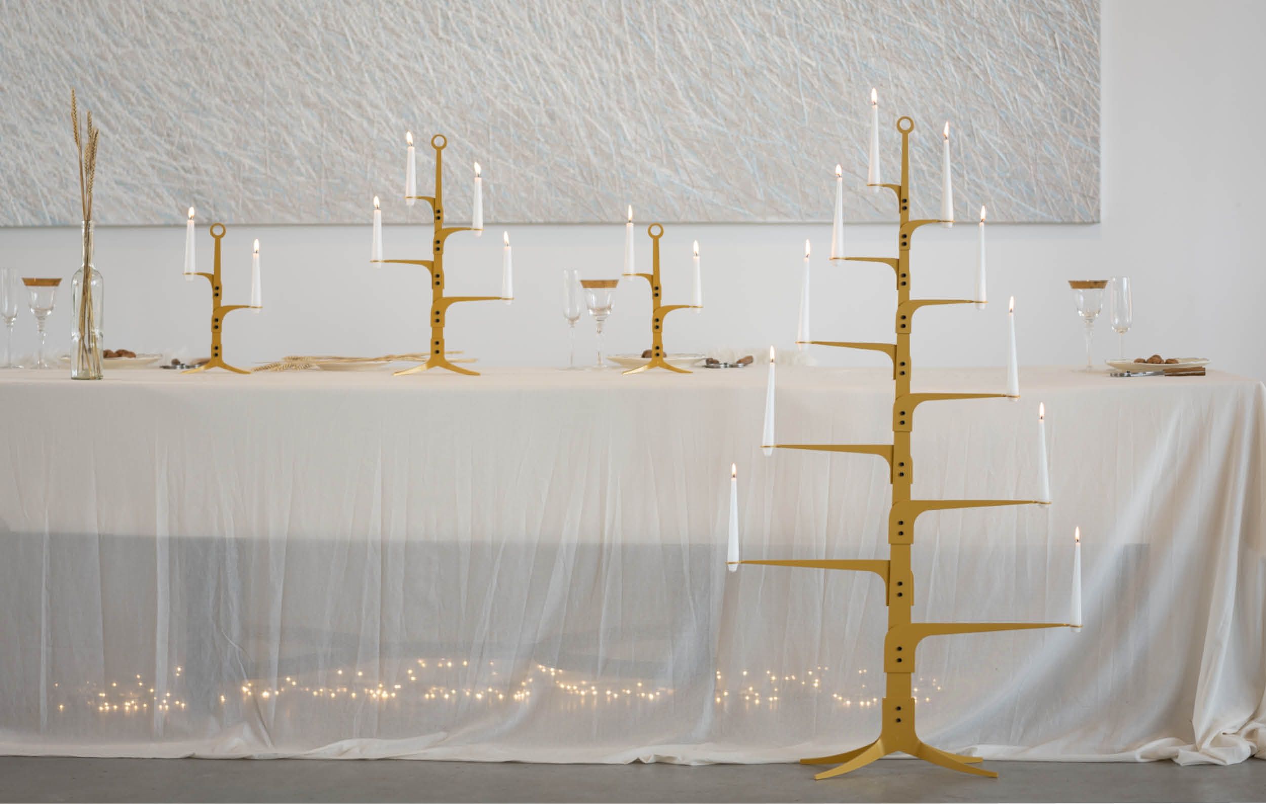 bij ore design in Heeten, dinertafel met wit transparant tafelkleed, kandelaren serie the ore glow op tafel, de kaarsen branden, tafel gedekt met glazen en bordjes met noten en de notenkrakers.