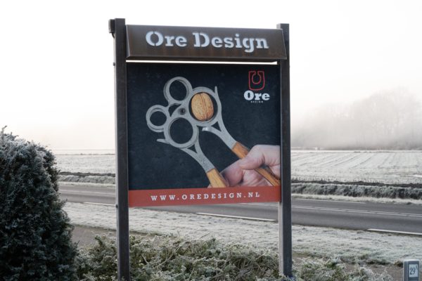 ore design reclamebord - Heetenseweg 29 - N332.oredesign.nl ontwikkelt handgemaakte keuken- en diningtools. Foto van bord in de mist, op het bord een foto van the Ore Nutcracker, vorst op het bord zichtbaar als ijsbloemen op de belettering.