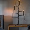 The Ore Glow_HARMONY met zwarte LED kaarsen, donker notenhouten stam en antraciet gecoate armen.