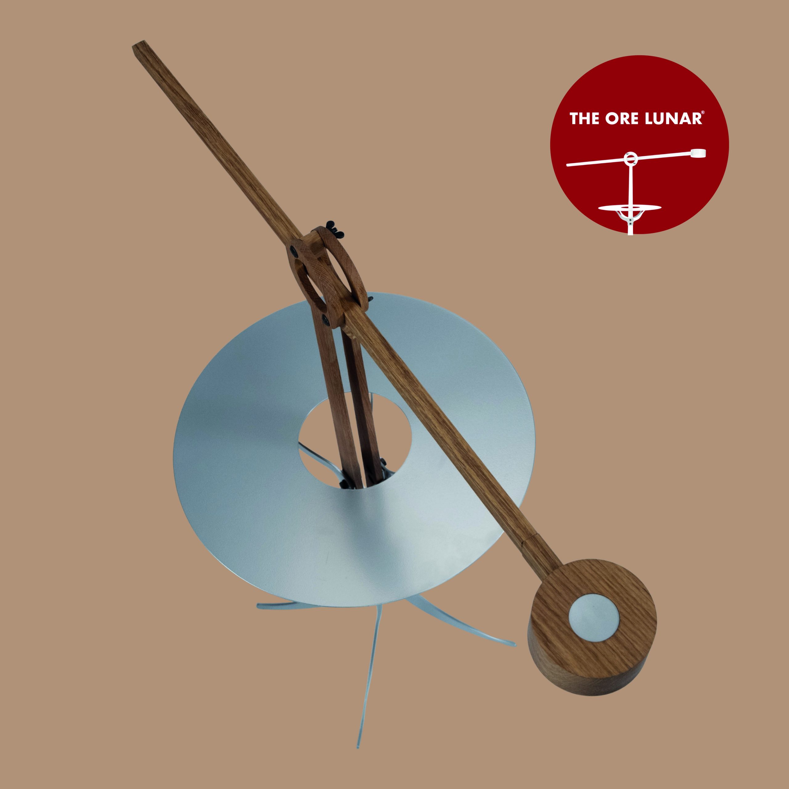 The Ore Lunar van bovenaf gezien, arm met lamp is uitgeschoven. Het blad en de voet zijn zilver gecoat metaal en de houder en arm met lapmp zijn van eikenhout gemaakt.
